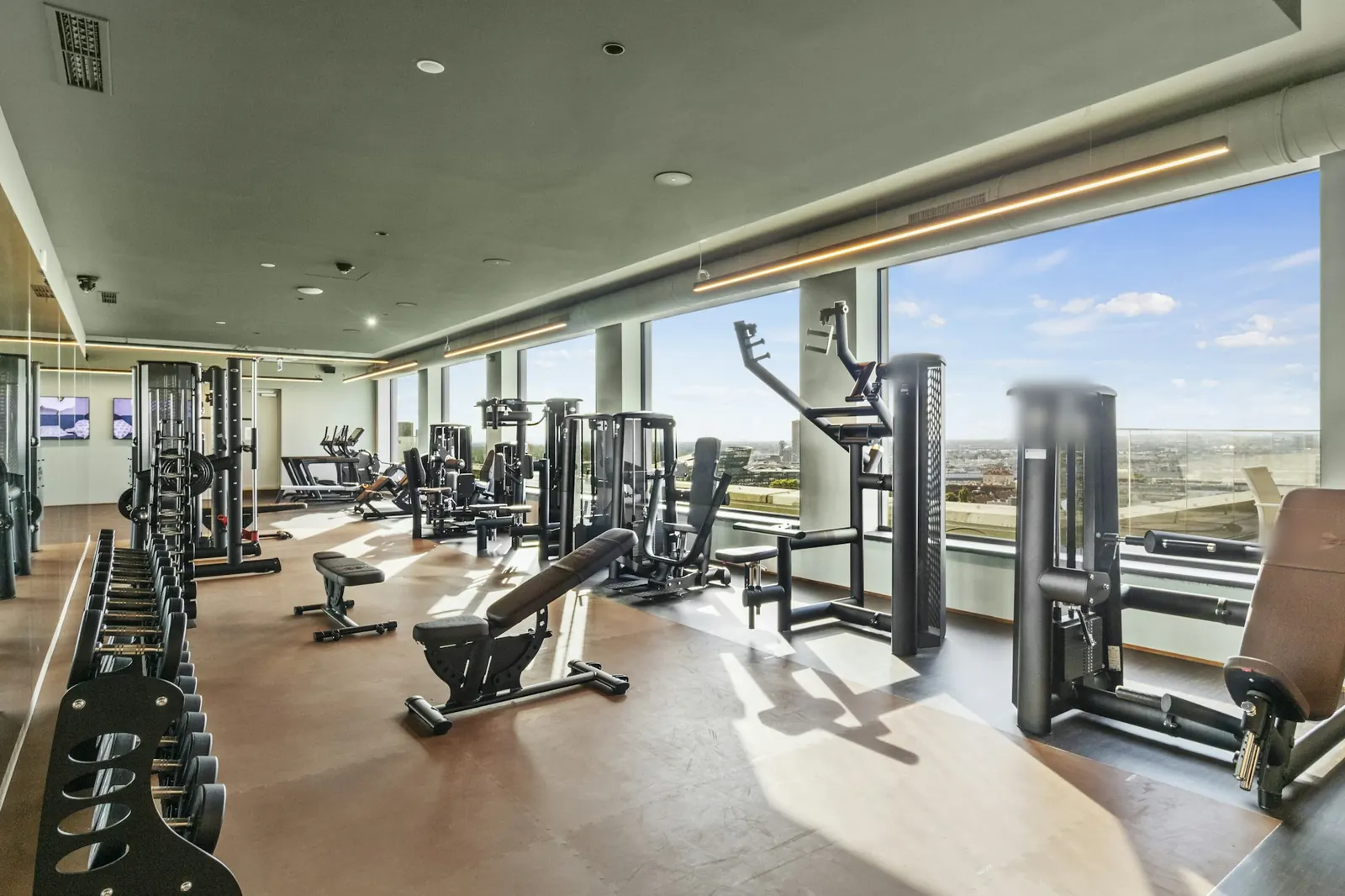 Academia corporativa com máquinas de musculação e vista para a cidade