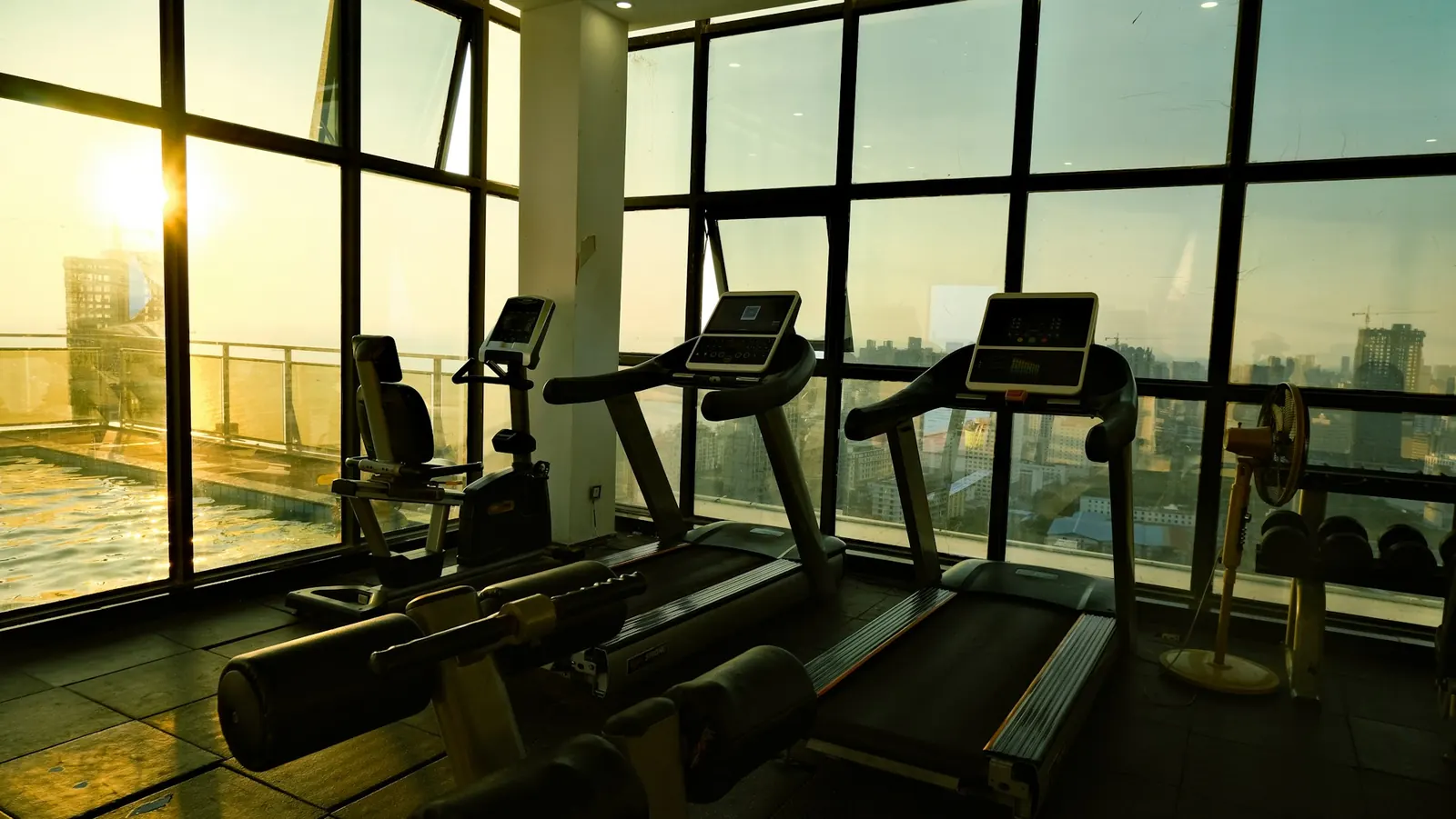 Academia de hotel com esteiras de frente para a cidade ao pôr do sol