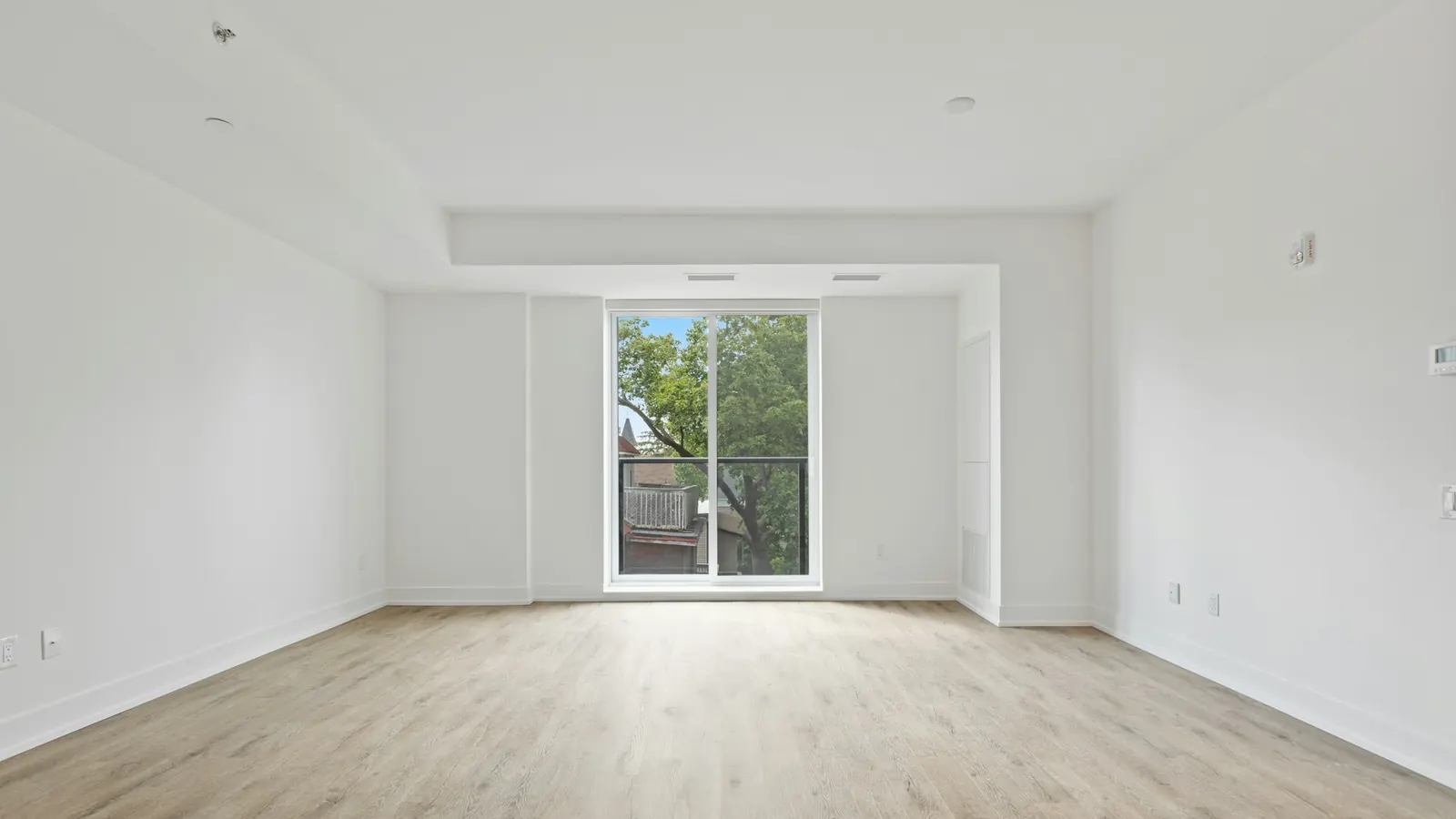 Sala vazia, com piso de madeira e janela ao fundo