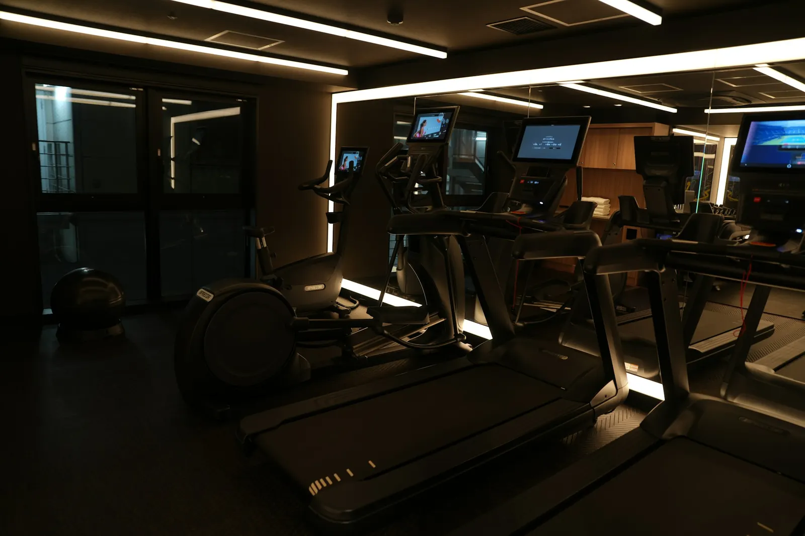 Academia escura com iluminação linear e esteiras